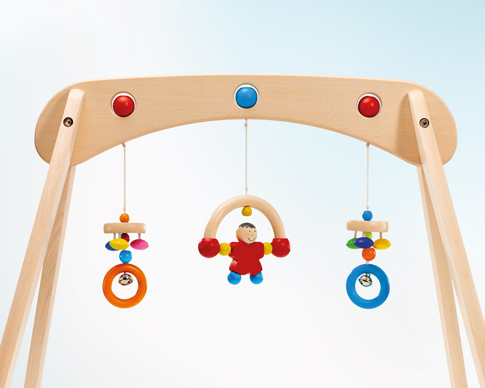 Houten babymobiel met kleurrijke hangende speeltjes, met een centrale figuur en zijringen. Gemaakt als stevige speeltrapeze van massief hout, biedt het duurzaamheid en charme om kleintjes te plezieren.
